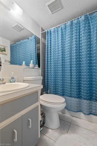 Bathroom featuring tile floors, a textured ceiling, oversized vanity, and toilet