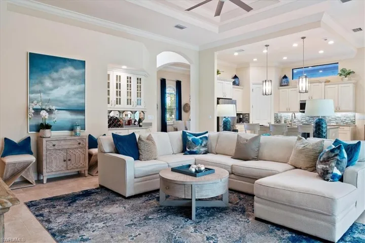 Living room with visible vents, arched walkways, tile patterned flooring, crown molding, and recessed lighting