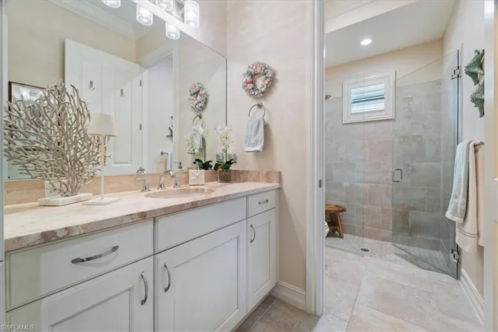 Full bathroom featuring crown molding, vanity, a shower stall, tile patterned flooring, and baseboards