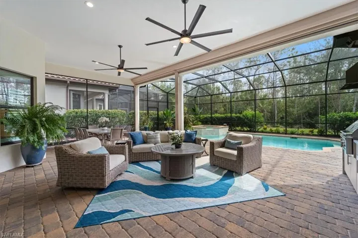 View of patio with glass enclosure, a pool with connected hot tub, and outdoor lounge area