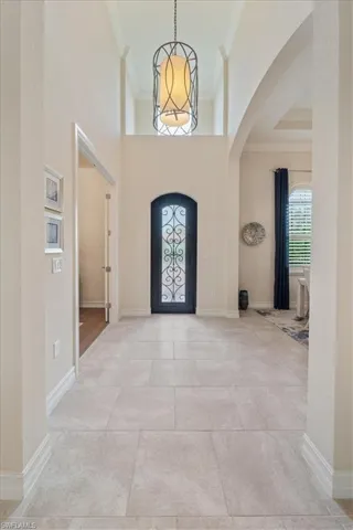 Foyer entrance featuring baseboards, a notable chandelier, arched walkways, and crown molding