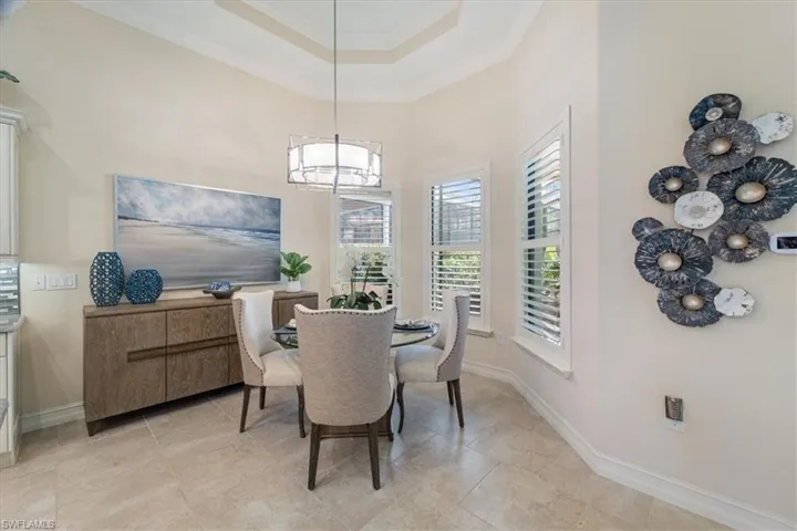 Dining space featuring baseboards, a tray ceiling, a towering ceiling, and crown molding
