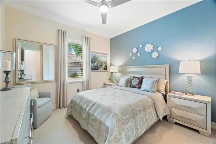 Bedroom with ceiling fan, ornamental molding, and light colored carpet