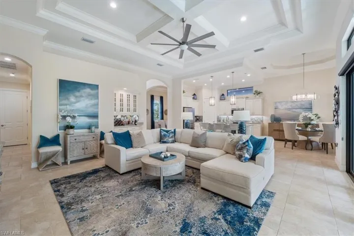 Living area with ornamental molding, arched walkways, visible vents, and coffered ceiling