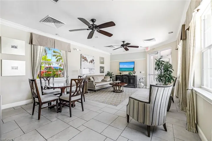 Tiled dining space featuring ceiling fan and ornamental molding
