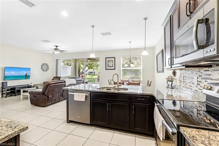 Kitchen with stainless steel appliances, tasteful backsplash, sink, ceiling fan, and hanging light fixtures