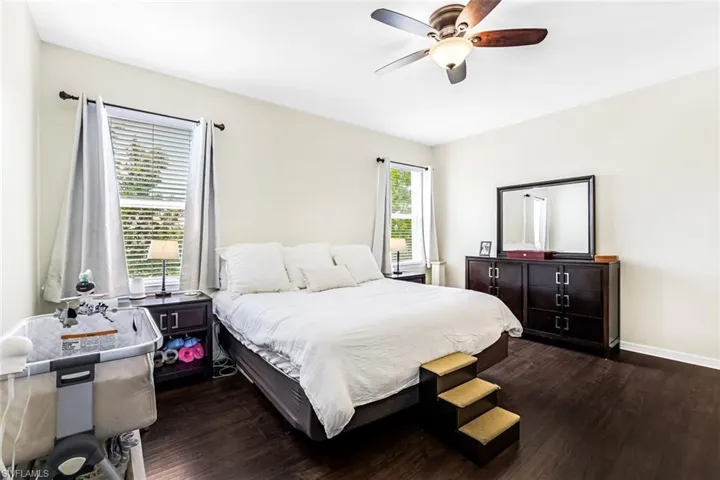 Bedroom with multiple windows, dark hardwood / wood-style floors, and ceiling fan