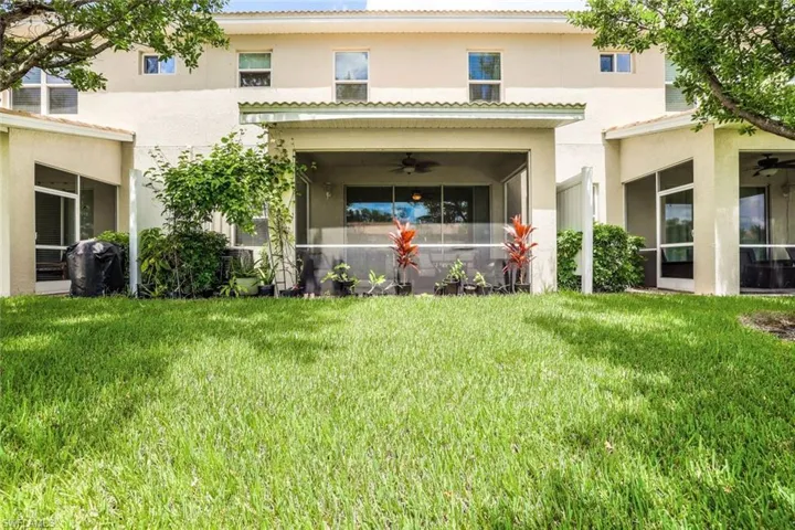 Rear view of house with ceiling fan and a yard