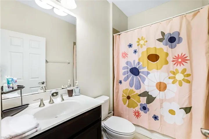 Bathroom featuring curtained shower, vanity, and toilet