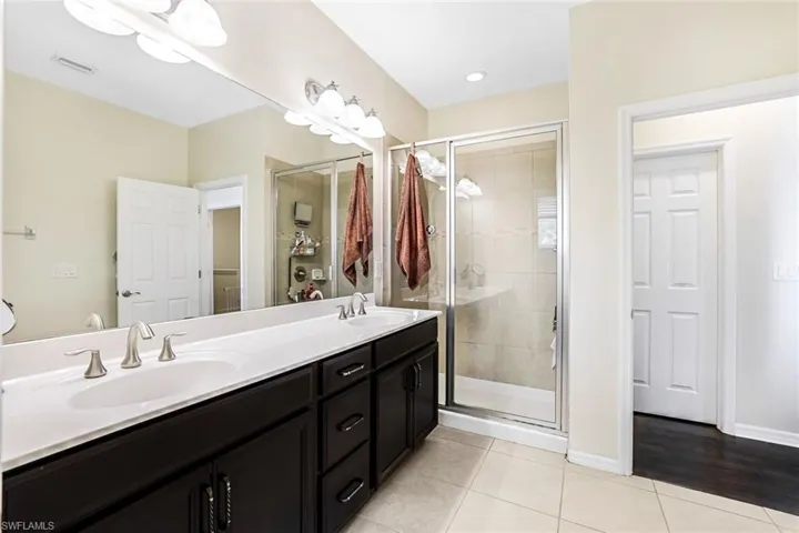 Bathroom with tile patterned flooring, a shower with door, and vanity