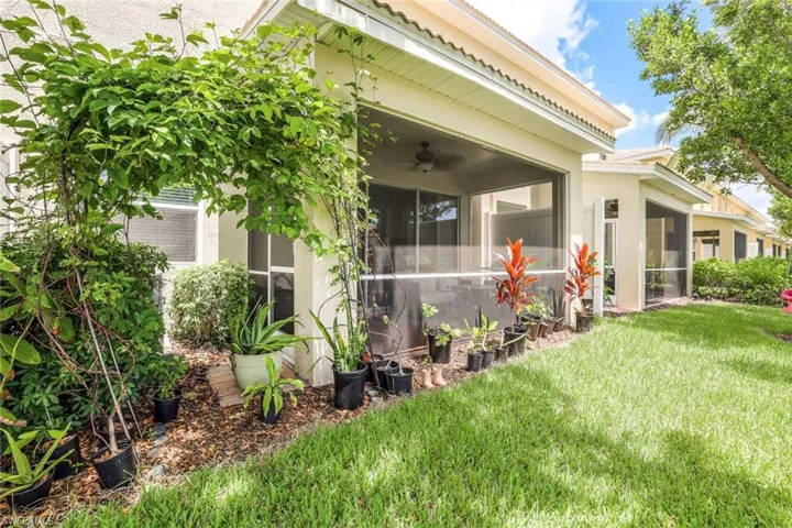 Rear view of property featuring ceiling fan, a sunroom, and a lawn