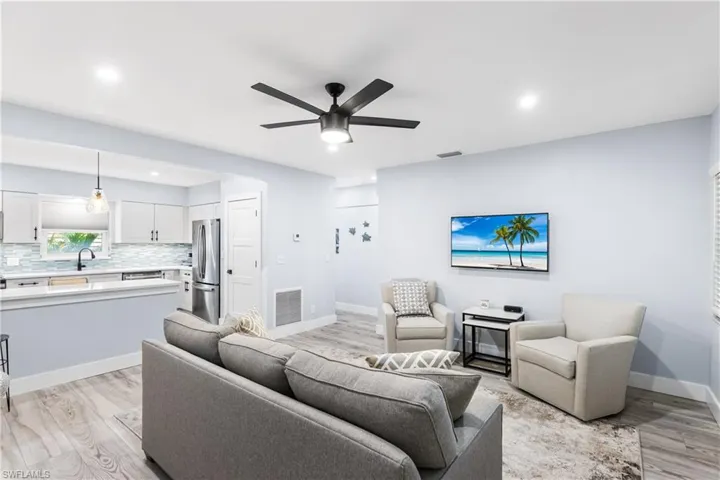 Living room with visible vents, baseboards, light wood-style floors, and a ceiling fan