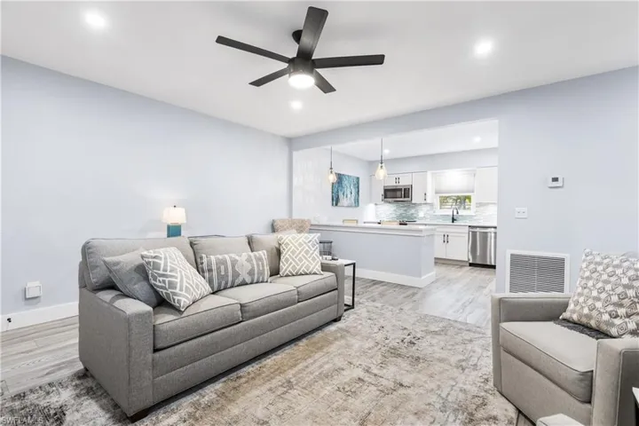 Living room featuring visible vents, baseboards, ceiling fan, and light wood finished floors
