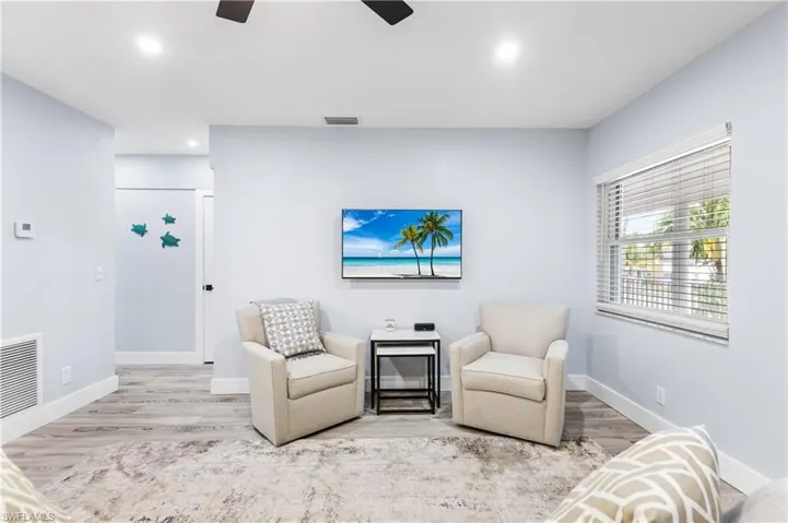 Sitting room with visible vents, wood finished floors, baseboards, and ceiling fan