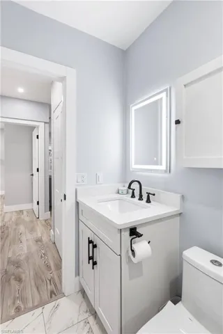 Half bath featuring vanity, toilet, and marble finish floor