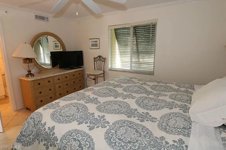 Bedroom with ornamental molding, light tile patterned floors, and ceiling fan