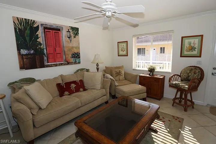 Tiled living room featuring crown molding and a ceiling fan