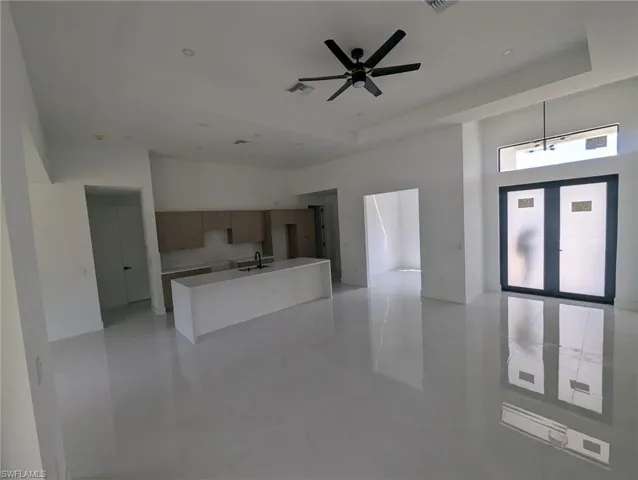 Kitchen with a tray ceiling, ceiling fan, decorative light fixtures, and sink