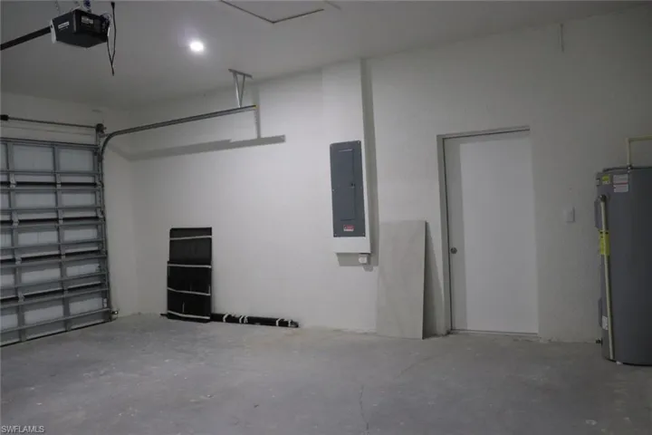 Garage with electric panel, a garage door opener, and water heater