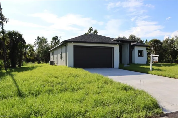 View of front of property featuring a front yard, a garage, and central AC unit