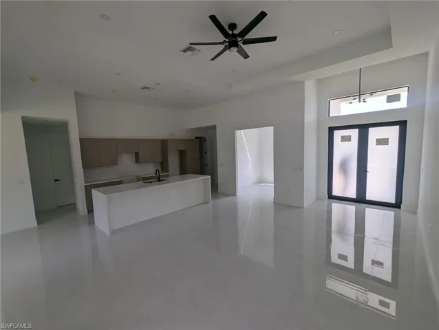 Kitchen with a tray ceiling, sink, pendant lighting, and ceiling fan