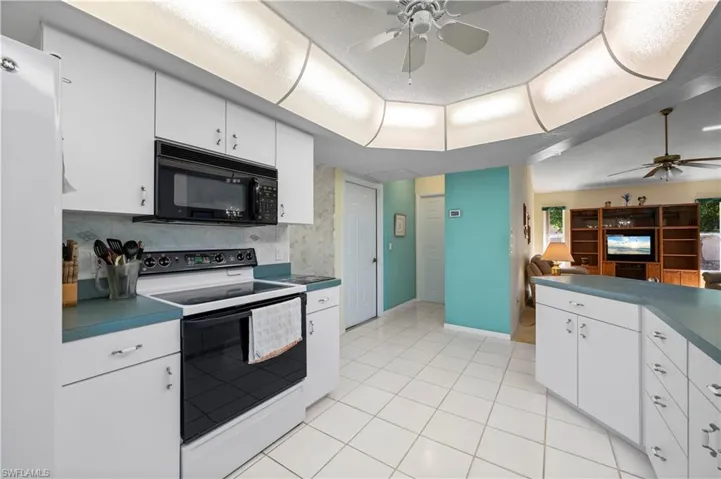 Bedroom with an office area, light colored carpet, ceiling fan and two walk in closets.