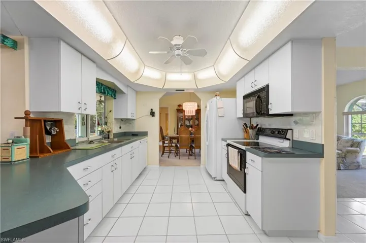 Bathroom with dual vanity, tile patterned floors, a shower stall, and ceiling fan