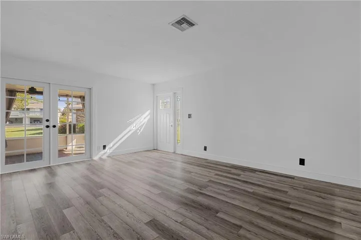 Unfurnished living room with wood finished floors and french doors
