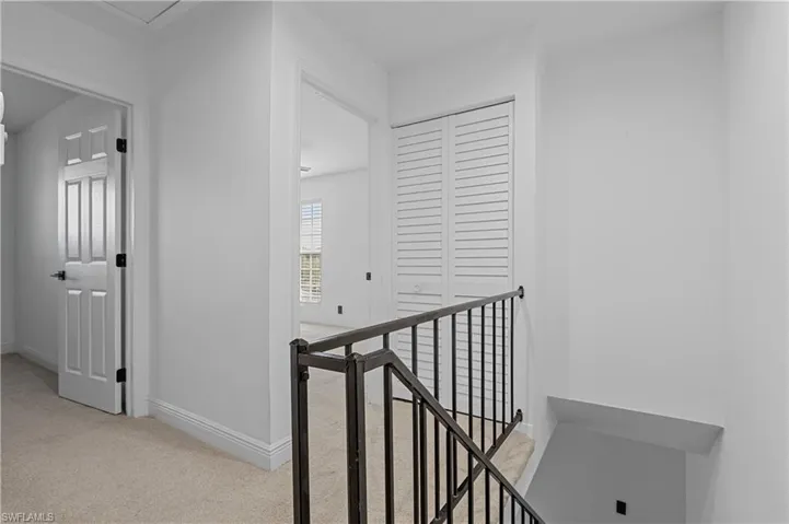 Hallway featuring light carpet and an upstairs landing