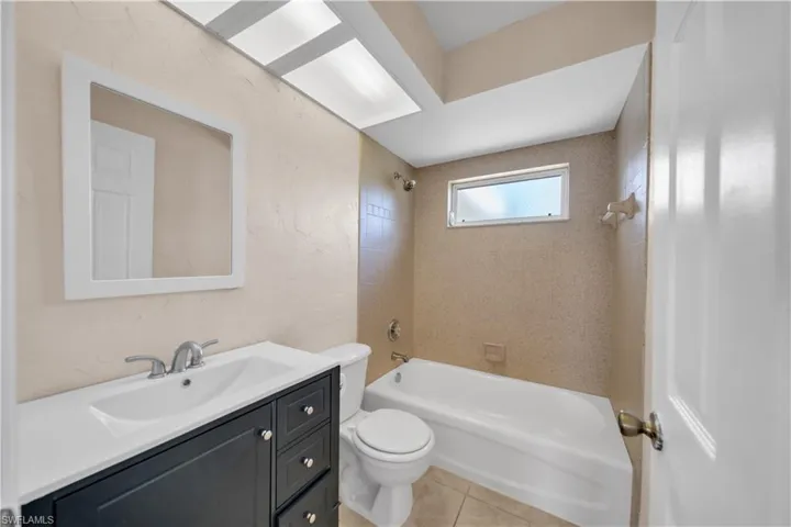 Bathroom featuring a white bathtub and a dark wood-finish vanity with a white countertop