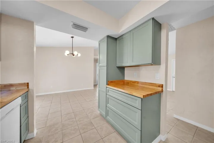 Kitchen featuring sage green cabinetry, wood-finish countertops, and square tile flooring