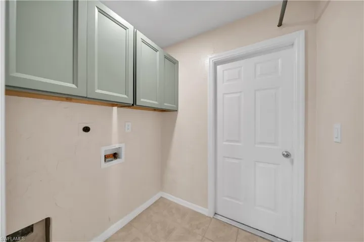 Utility area featuring tile flooring, neutral wall tones, and overhead cabinetry