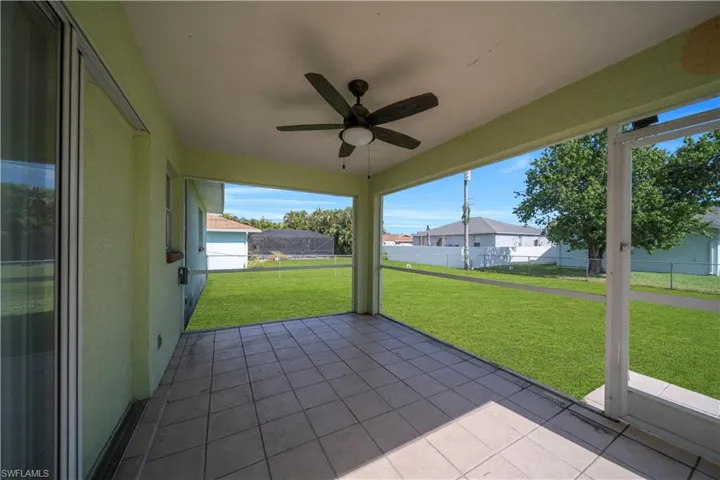 Screened outdoor patio featuring a ceiling fan, tiled flooring, and a sliding glass door
