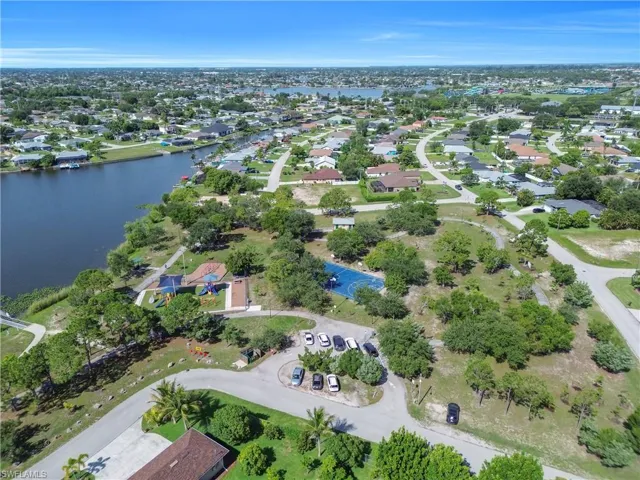 Expansive neighborhood featuring a large waterway, residential properties, varied landscaping, open spaces, and a recreational court