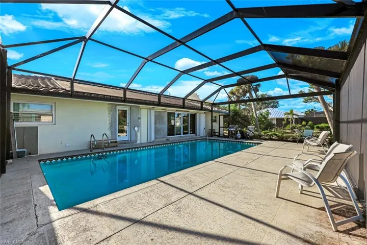 Outdoor pool with a patio area and glass enclosure