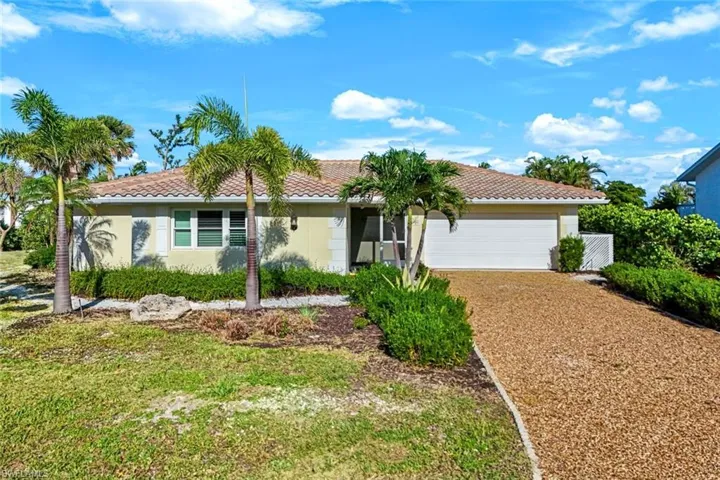Ranch-style house with a tile roof, a garage, driveway, and stucco siding