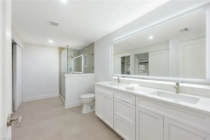 Bathroom with a stall shower, double vanity, and recessed lighting