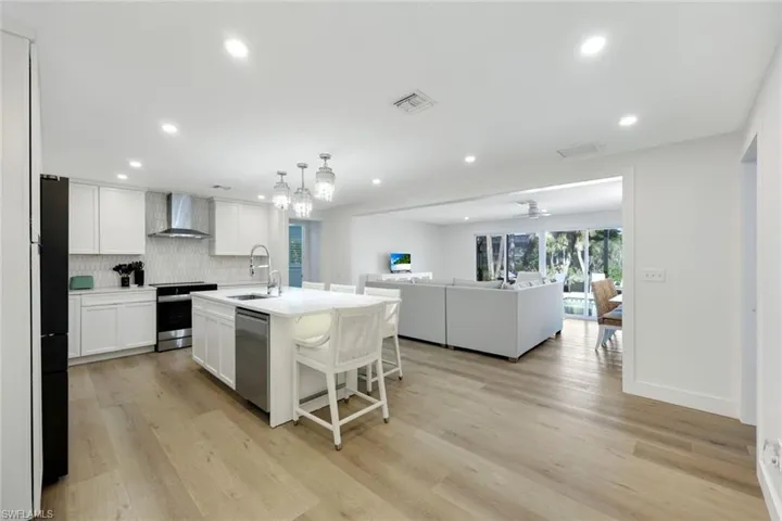 Kitchen with backsplash, white cabinetry, open floor plan, light wood-type flooring, and recessed lighting