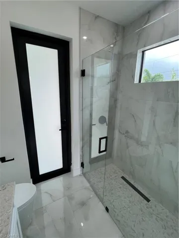 Bathroom featuring tile flooring, a shower with shower door, toilet, and vanity
