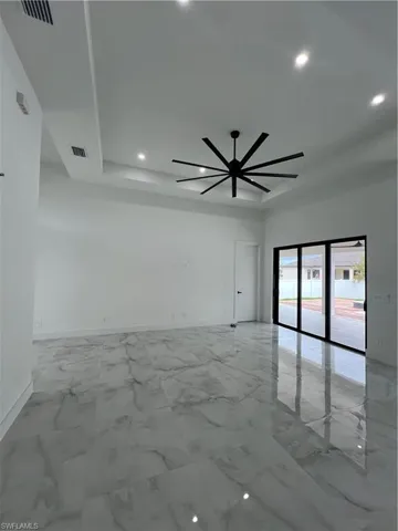 Tiled empty room featuring ceiling fan and a raised ceiling