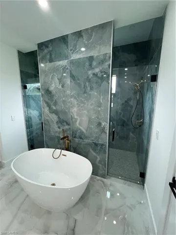Bathroom featuring walk in shower, tile flooring, and tile walls