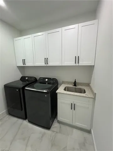 Washroom featuring sink, separate washer and dryer, light tile flooring, and cabinets
