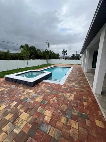 View of pool with a patio and an in ground hot tub