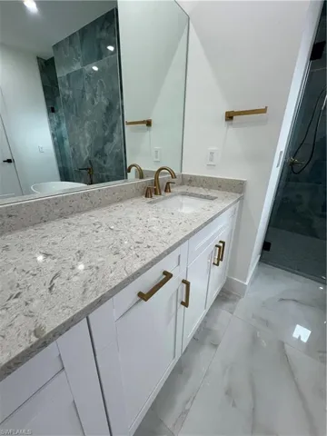 Bathroom with a tile shower, tile flooring, and vanity