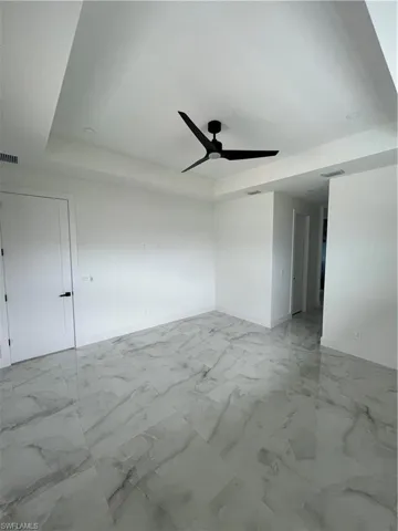 Tiled empty room featuring a raised ceiling and ceiling fan