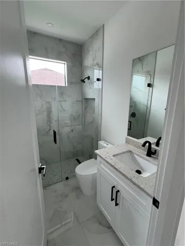 Bathroom featuring tile floors, an enclosed shower, oversized vanity, and toilet