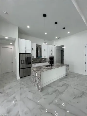 Kitchen with light tile floors, hanging light fixtures, white cabinetry, and a center island