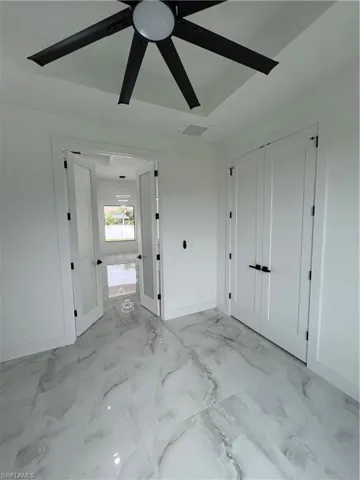 Unfurnished bedroom with ceiling fan and light tile flooring