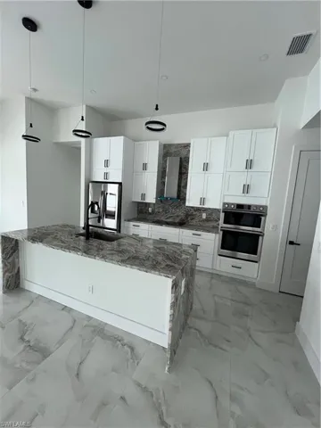 Kitchen featuring decorative light fixtures, white cabinetry, and light tile floors