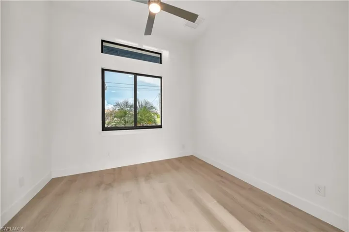Light wood-finish flooring, white walls, and a modern ceiling fan